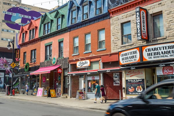 Une rue bordée de bâtiments aux couleurs vives, où se trouve notamment un restaurant appelé « Charcuterie Hebraïque ».