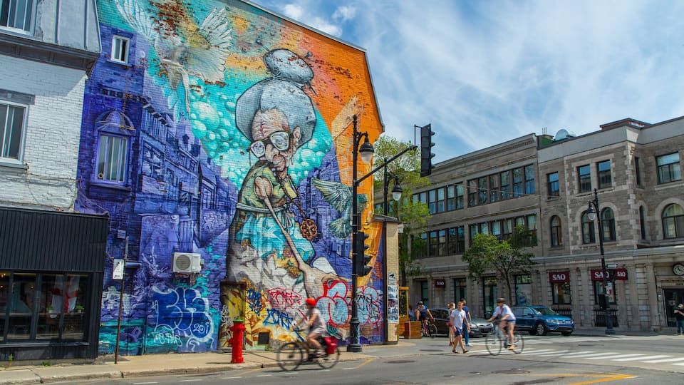 A vibrant mural on a building, a red fire hydrant, and a street with pedestrians and cyclists.