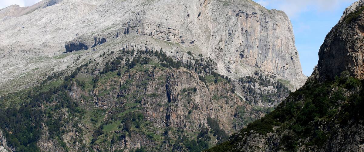 A rugged mountain with a prominent peak, steep slopes, and sparse vegetation.