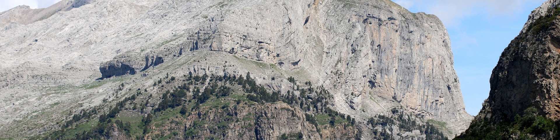 A rugged mountain with a prominent peak, steep slopes, and sparse vegetation.