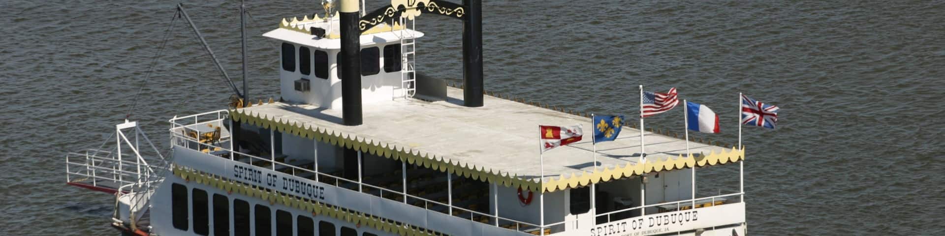 A large steamboat named 'Spirit of Dubuque' with multiple flags, including the American flag, on a body of water.