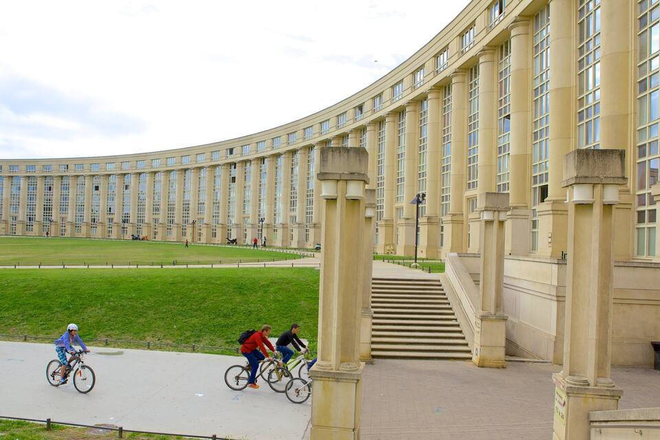 A large, curved building with columns and a grassy courtyard.