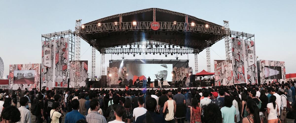 A large outdoor concert stage with a crowd of people in front.