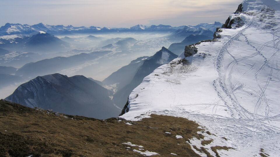 A snow-covered mountain ridge with a valley below.