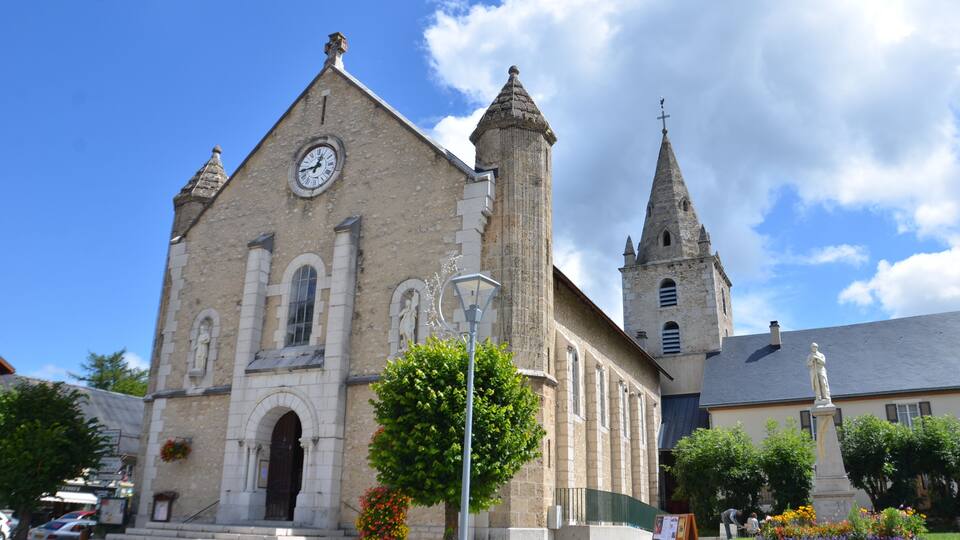 A historic church with a clock tower and a statue in front.