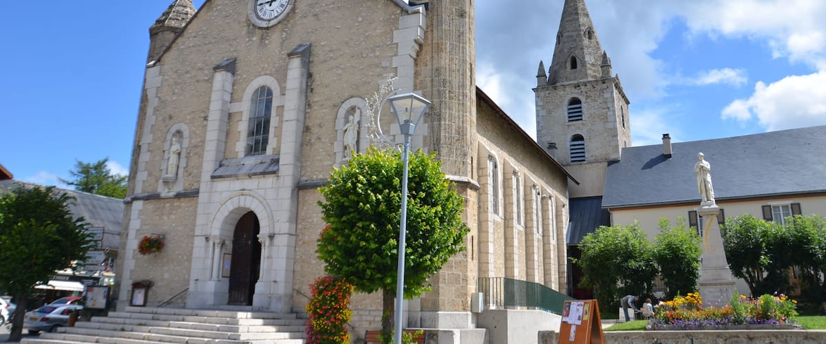 A historic church with a clock tower and a statue in front.