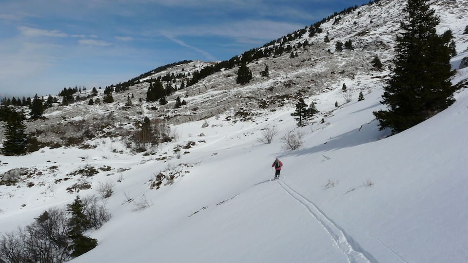 A snowy mountain landscape with a skier descending a slope.