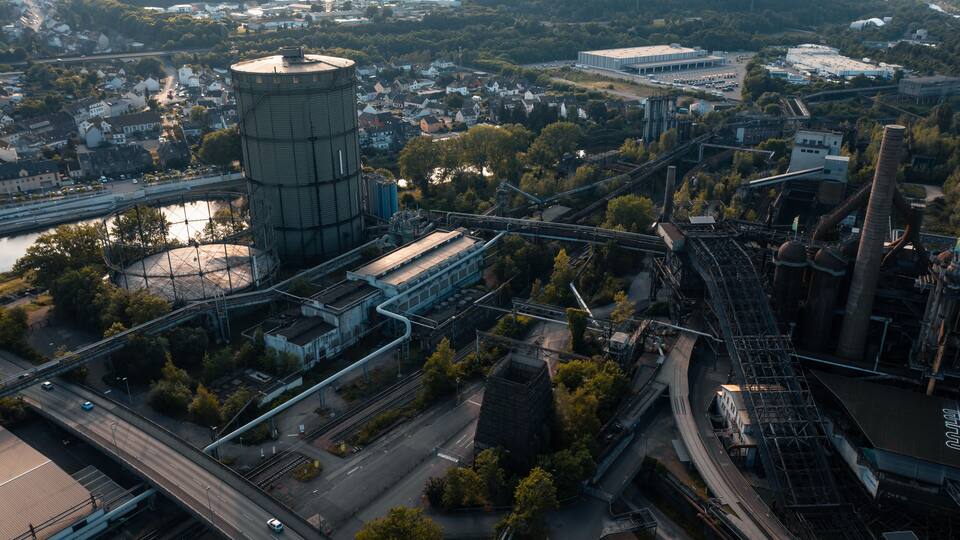 An industrial area with a large water tower, railway tracks, and a bridge.