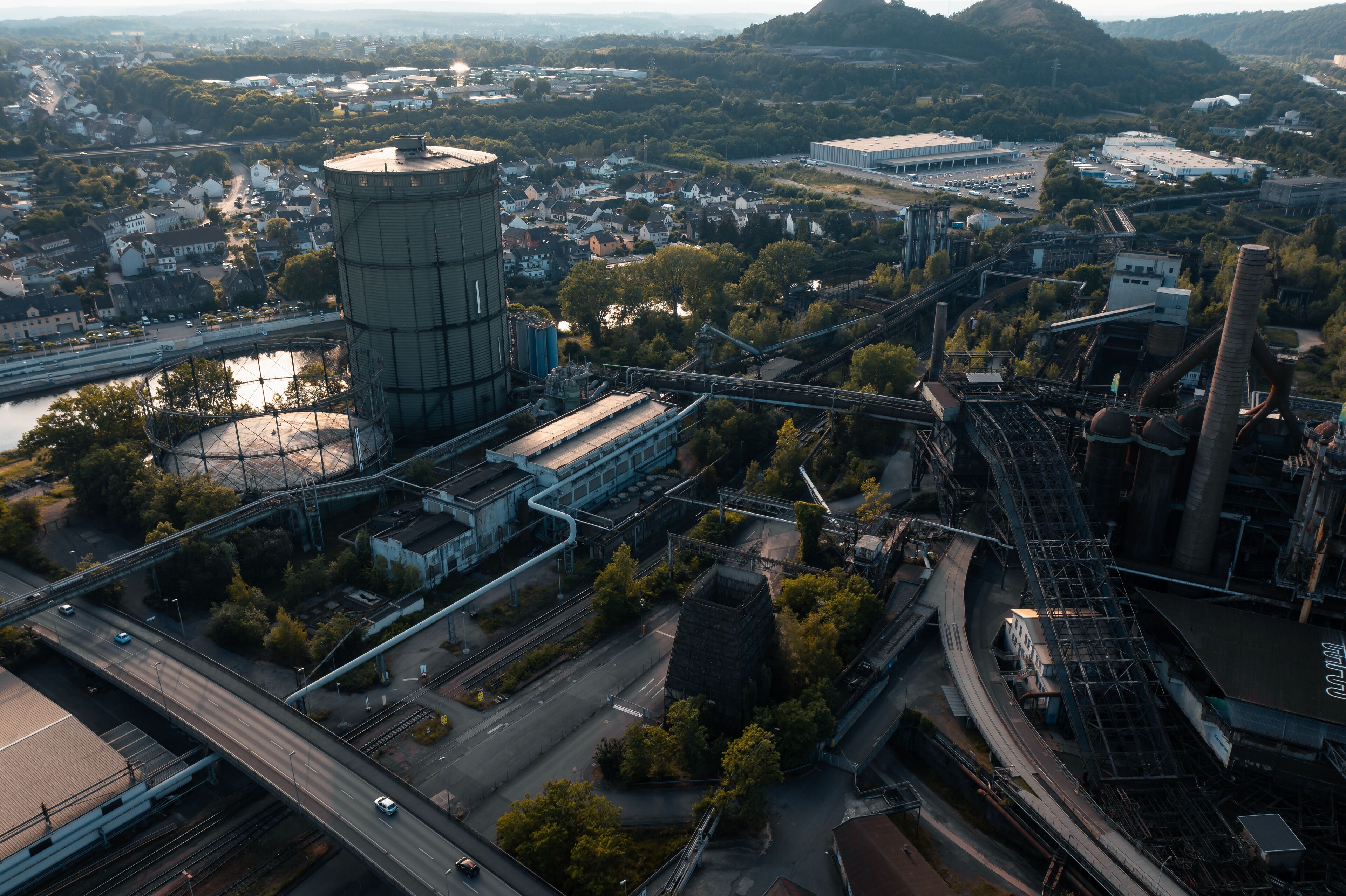 An industrial area with a large water tower, railway tracks, and a bridge.