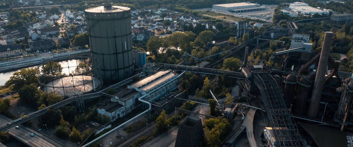 An industrial area with a large water tower, railway tracks, and a bridge.