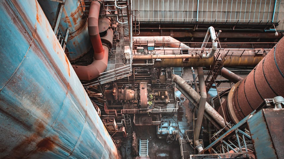 A large industrial facility with rusted metal tanks and pipes.