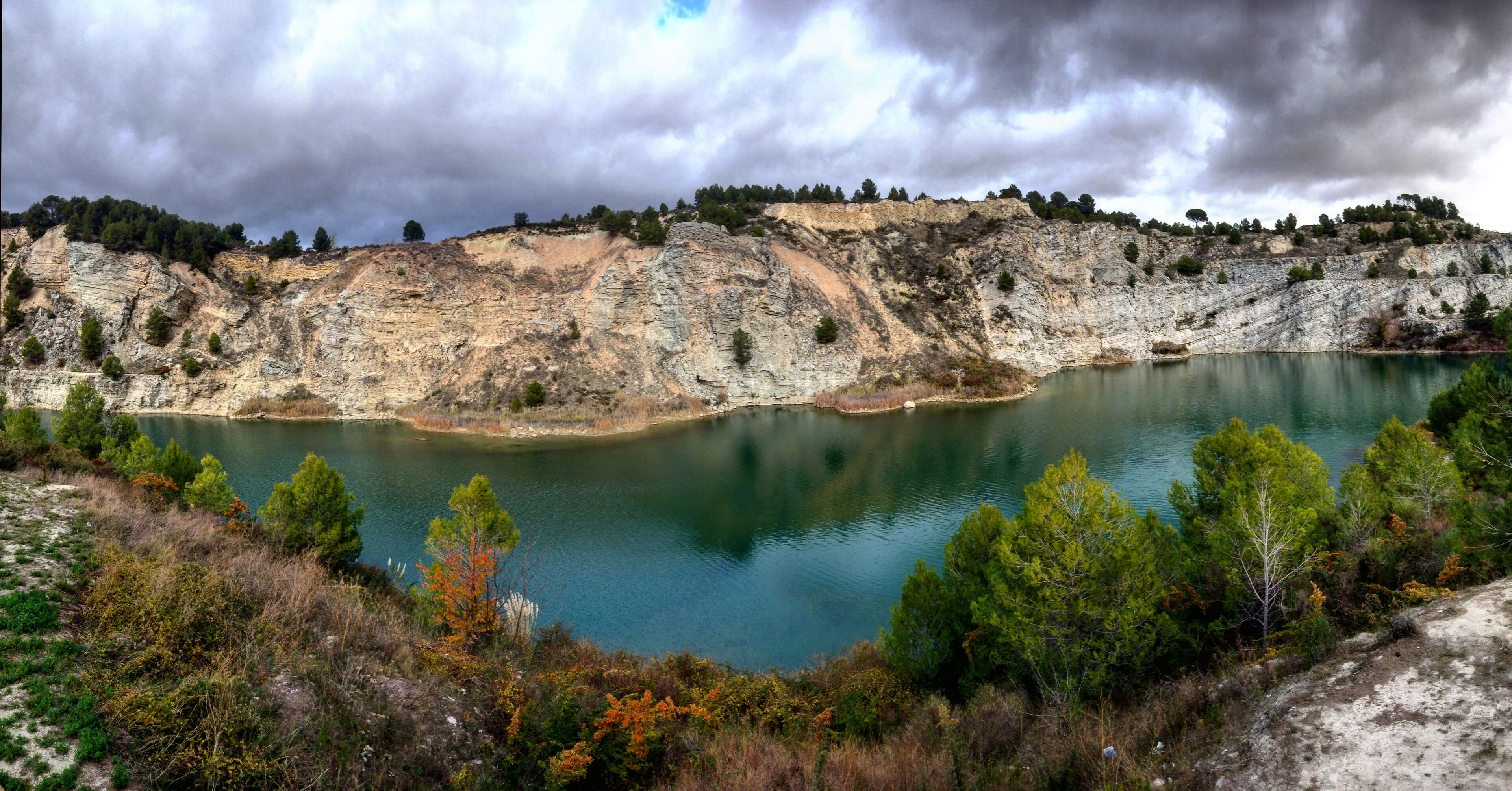 A lake surrounded by rocky cliffs and sparse vegetation.