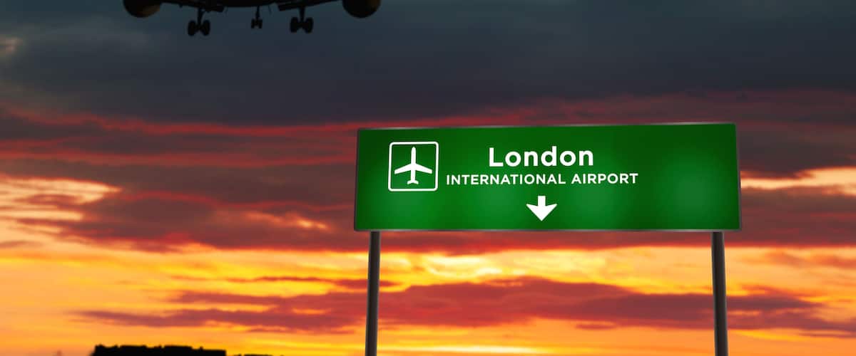 An airplane flying over a sunset with a sign for London International Airport.