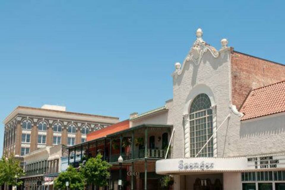 Un edificio histórico con fachada blanca y ventanas arqueadas, un balcón y un letrero que dice "Saguaro".