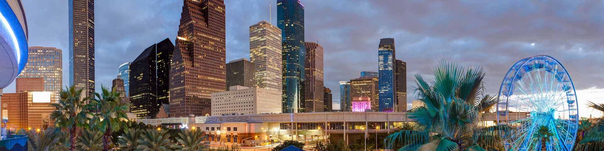 A cityscape with modern skyscrapers, a Ferris wheel, and a clock tower.