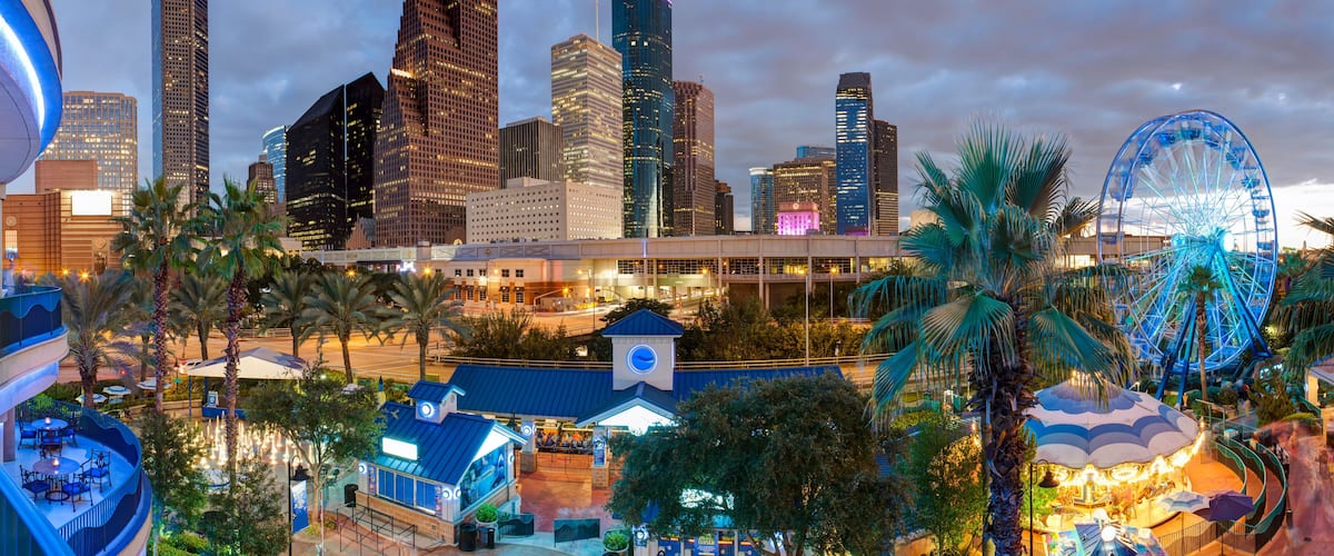 A cityscape with modern skyscrapers, a Ferris wheel, and a clock tower.