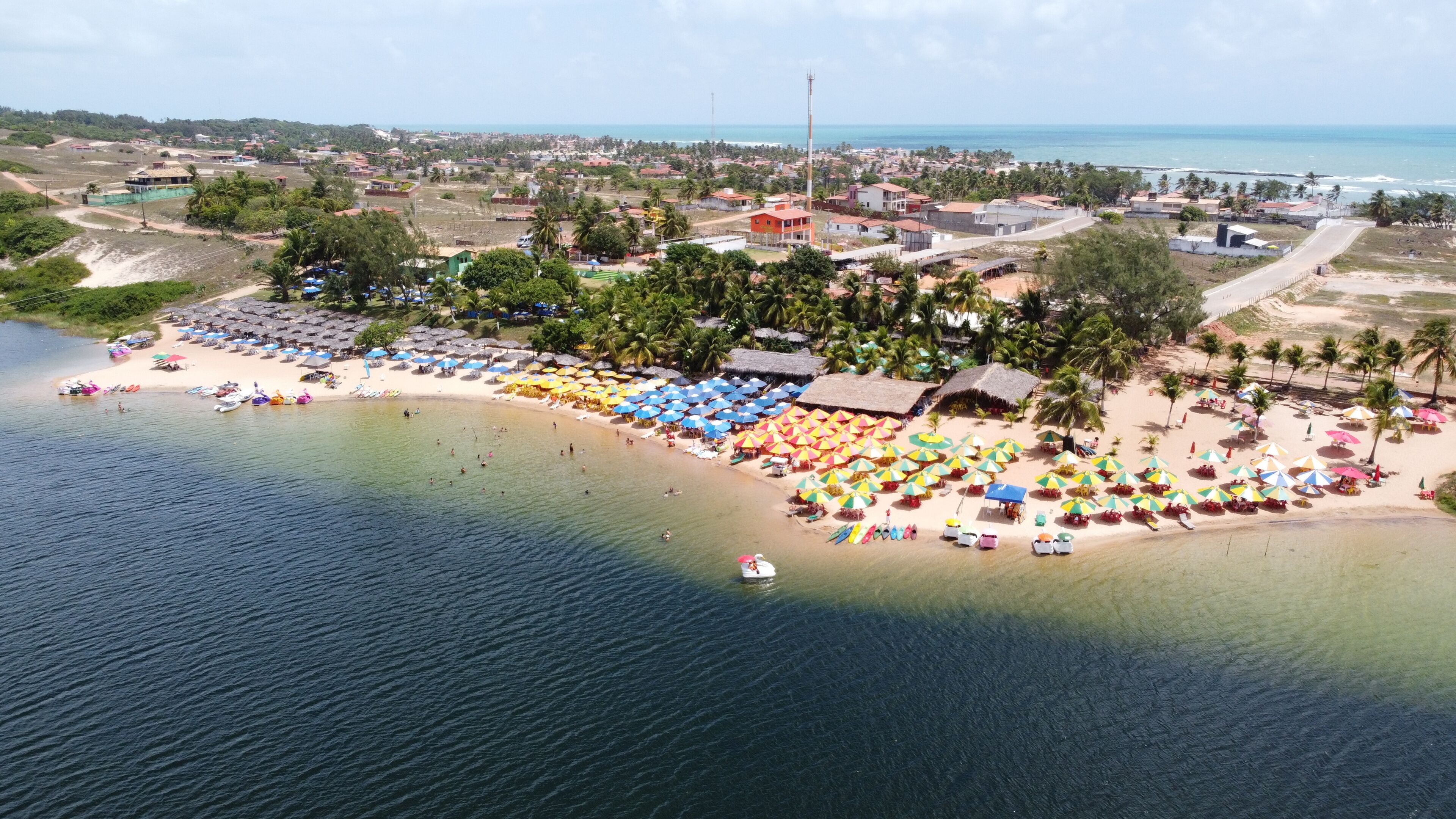 A coastal town with a beach, umbrellas, and a boat.