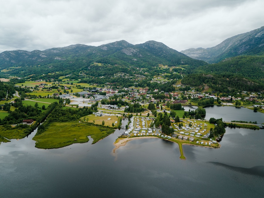 A lakeside town with a marina, surrounded by mountains and greenery.