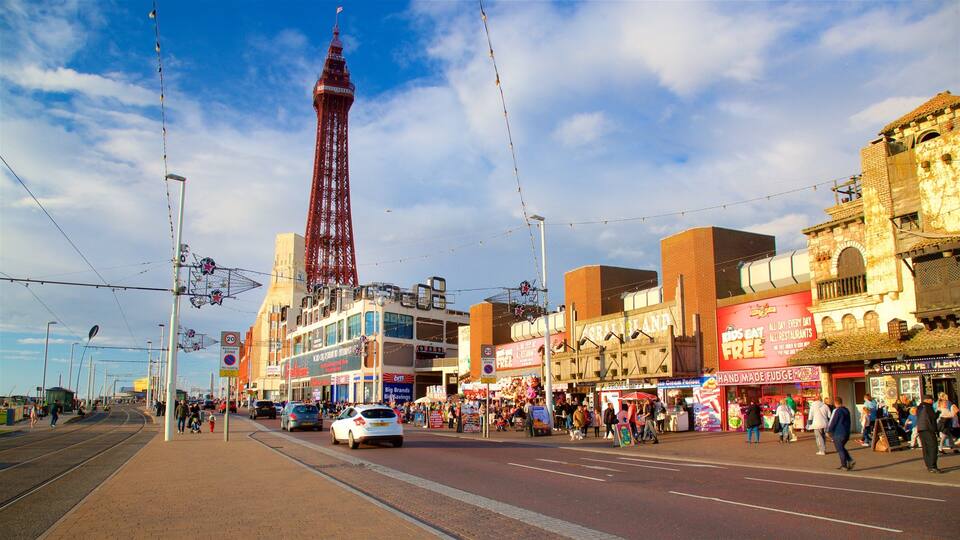A busy street with a prominent red tower, various shops, and a tram line.