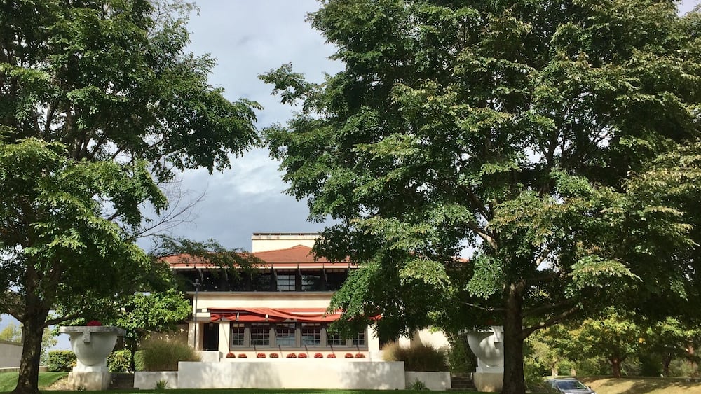 A modern house with a red roof, surrounded by lush green trees and a well-maintained lawn.