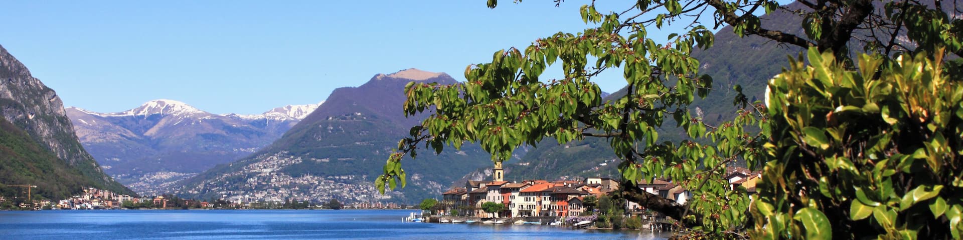 A lake with mountains in the background and a town on the shore.