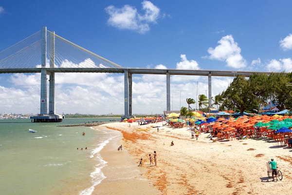 Une plage avec un grand pont en arrière-plan.