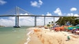Een strand met een grote brug op de achtergrond.