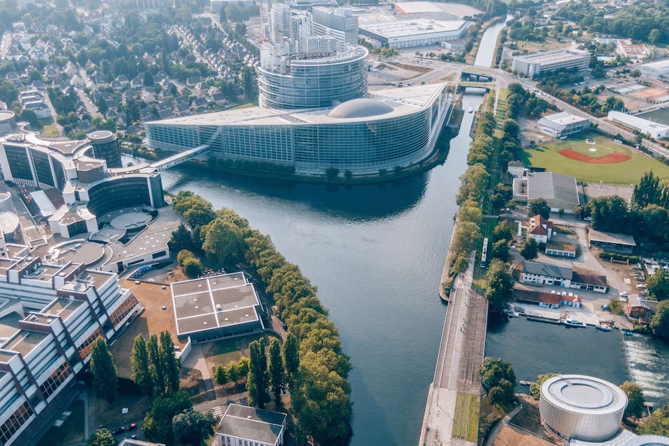 An aerial view of a modern city with a prominent circular building near a river.