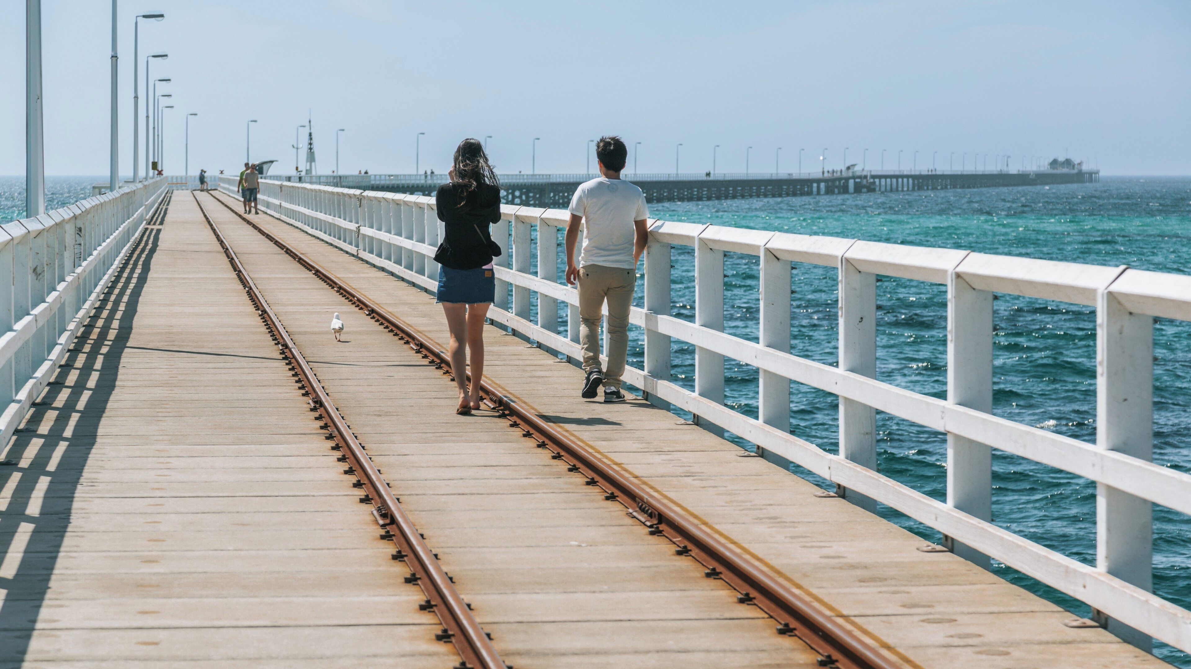 Visitors walk along Busselton Jetty in Western Australia enjoying the scenic coastal views during a sunny day