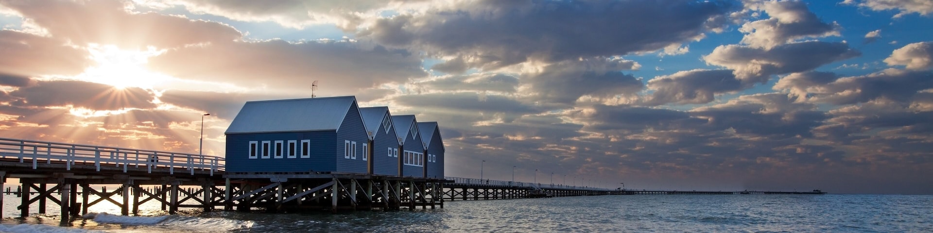 A pier extending into the sea with a building on it, under a partly cloudy sky.