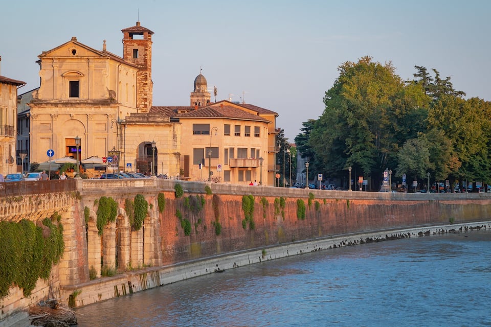 A historic building with a bell tower and a river in the foreground.