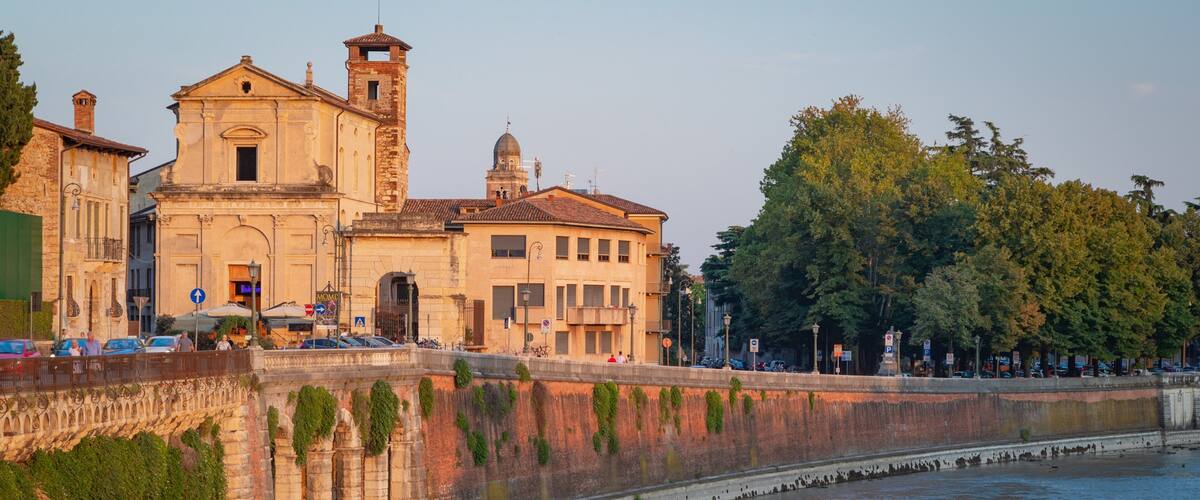 A historic building with a bell tower and a river in the foreground.
