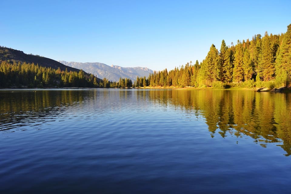 A calm lake surrounded by dense forests and mountains.