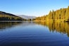 A calm lake surrounded by dense forests and mountains.