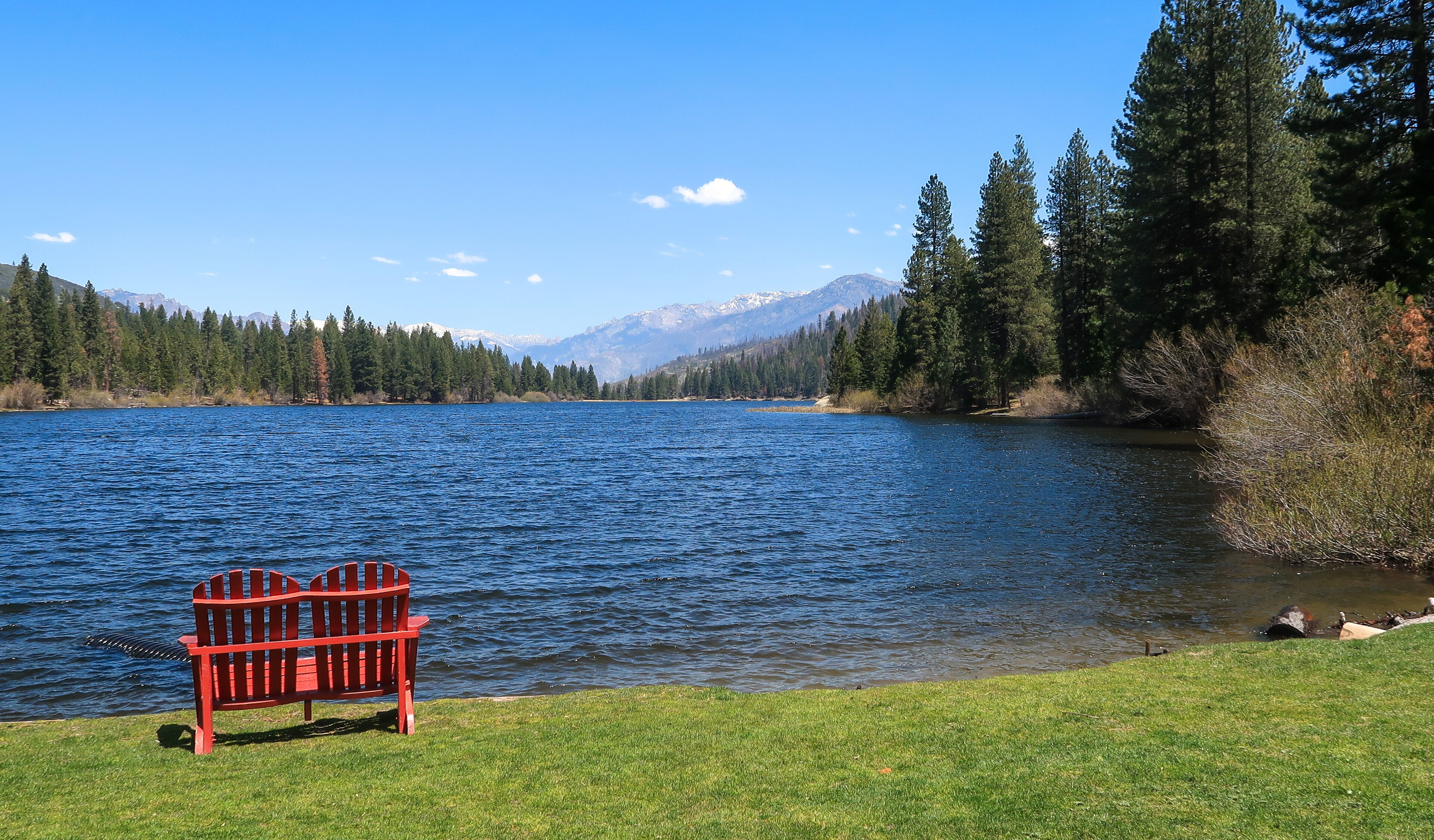 Landscape of red chair by Hume Lake with view of forest and mountains at Kings Canyon National Park in California