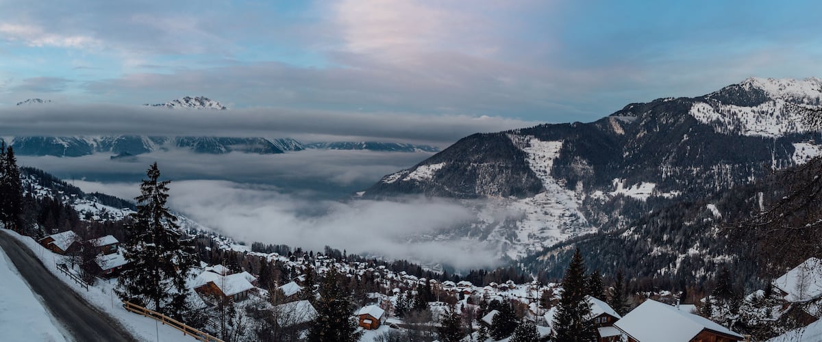 A snow-covered mountain range with a village at the base.