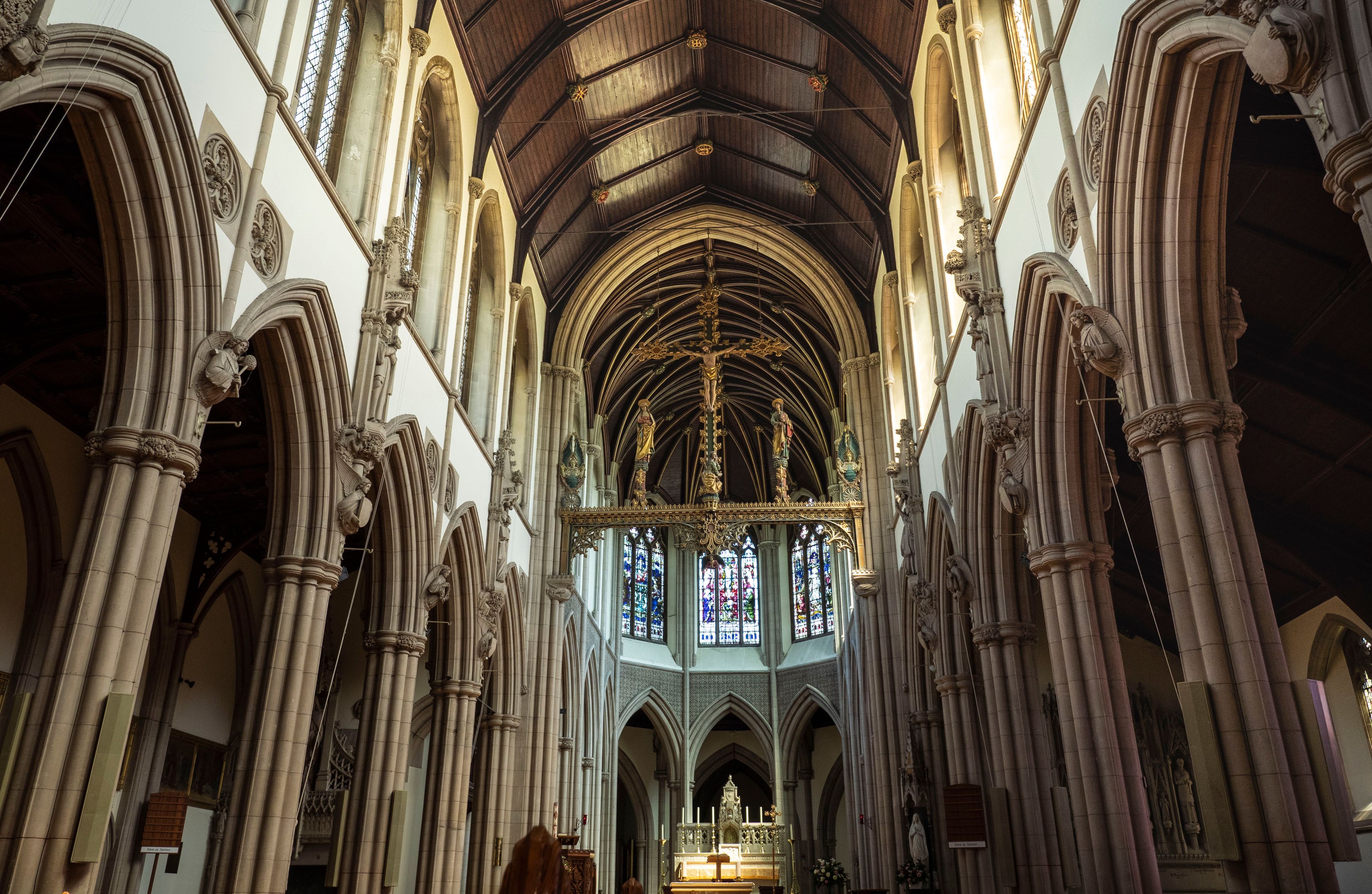 Interior de una catedral con arquitectura gótica, que incluye arcos apuntados, bóvedas de crucería y vidrieras.