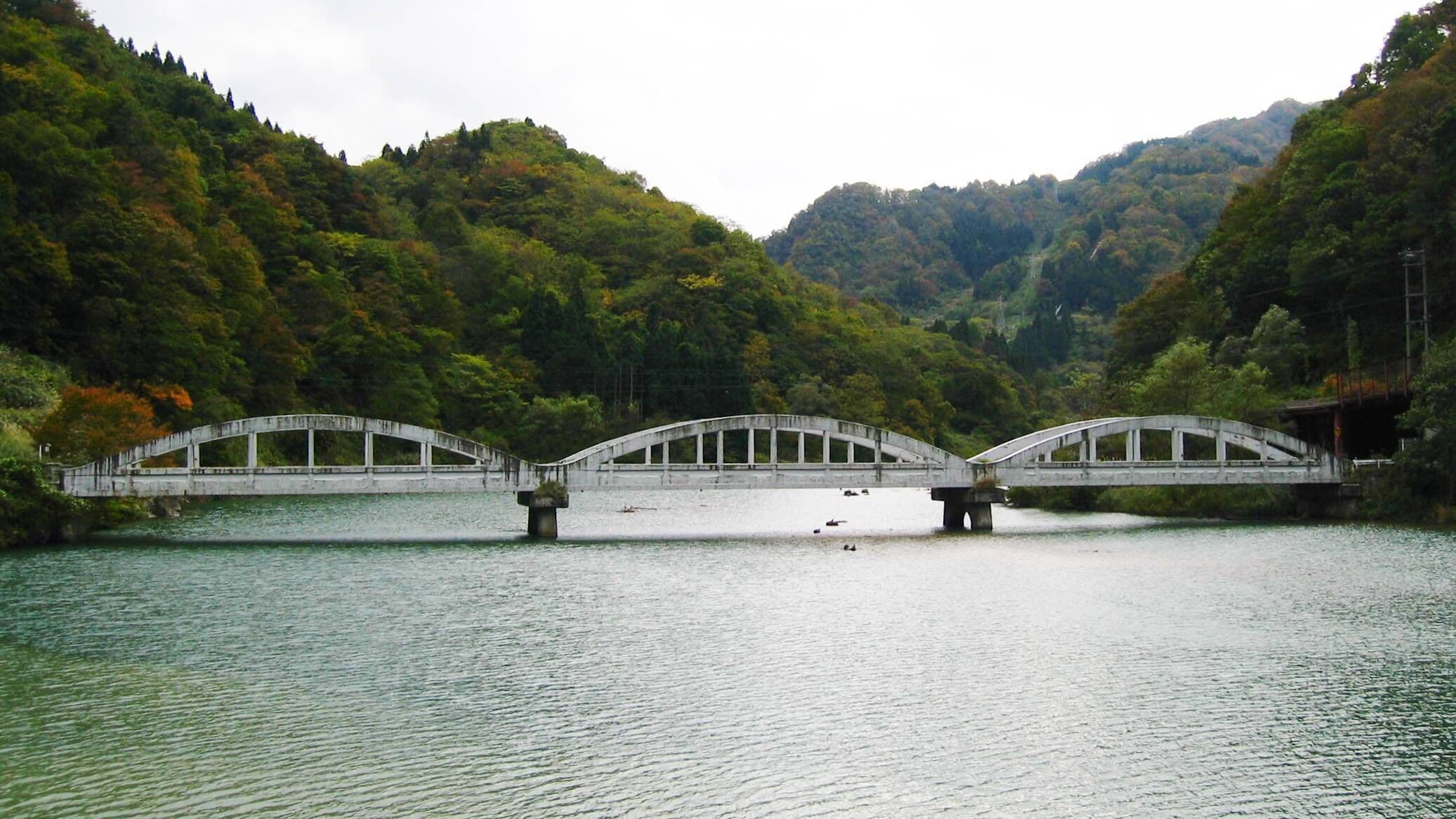 Un puente de piedra sobre un río tranquilo, rodeado de verdes colinas.