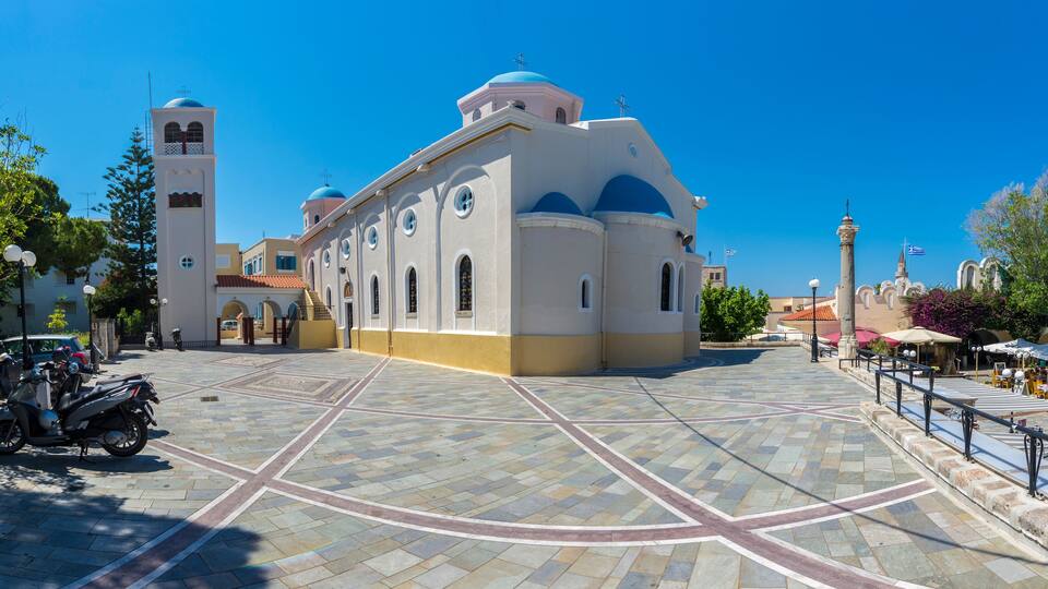 A church with a bell tower and a tiled courtyard.