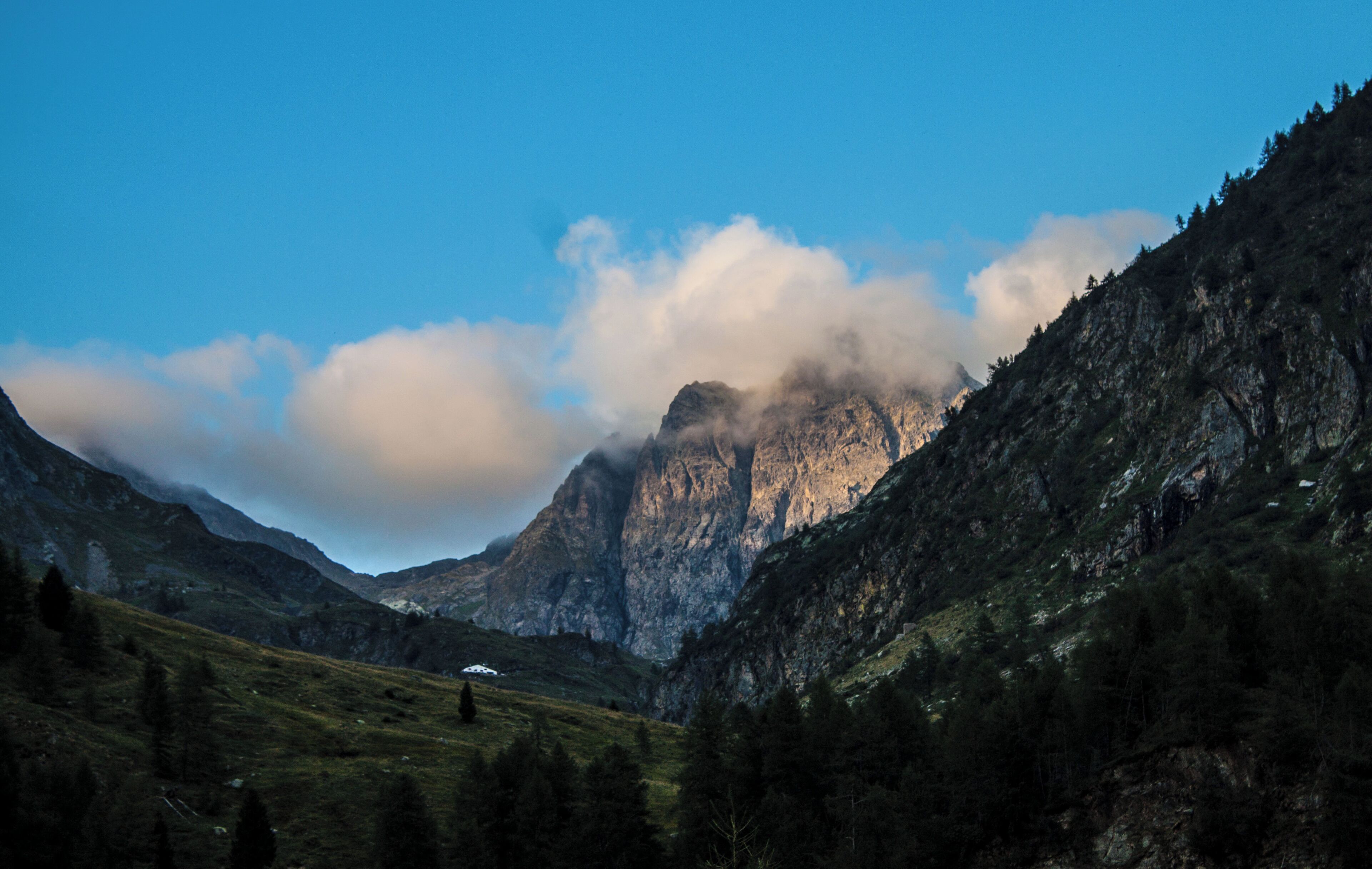 Ultimi raggi di sole di una giornata estiva si riflettono sulle pareti del monte Aga immerse in una coltre di nuvole.