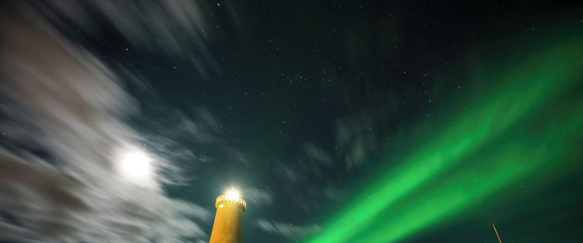 A lighthouse with green aurora borealis in the background.