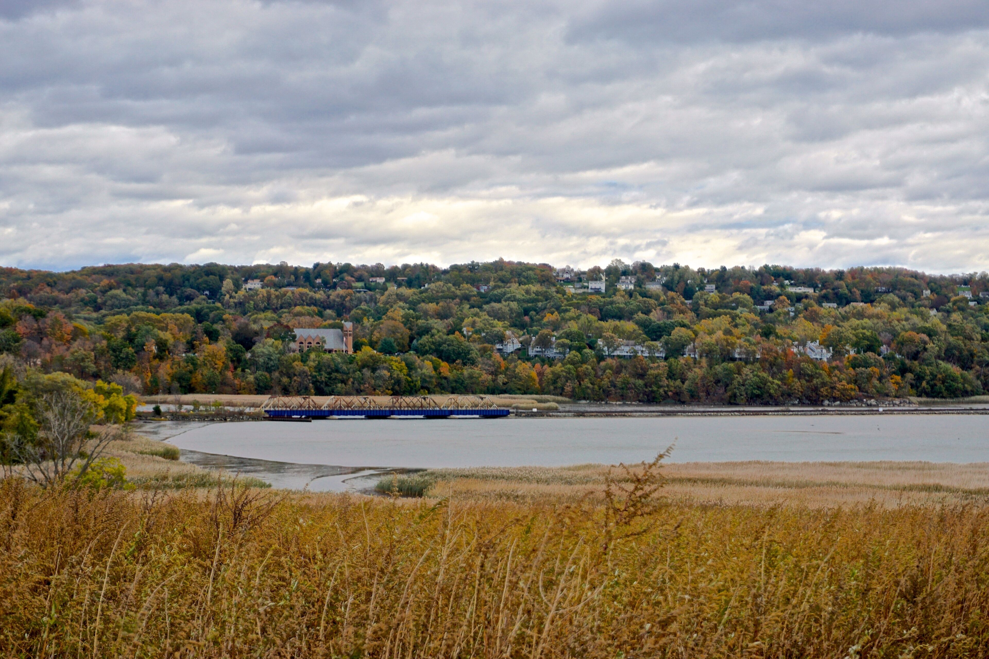 Westchester, NY, USA: A rail bridge spans an inlet on the Hudson River, with St. Augustine’s Roman Catholic Church, Ossining, NY, in the background. 