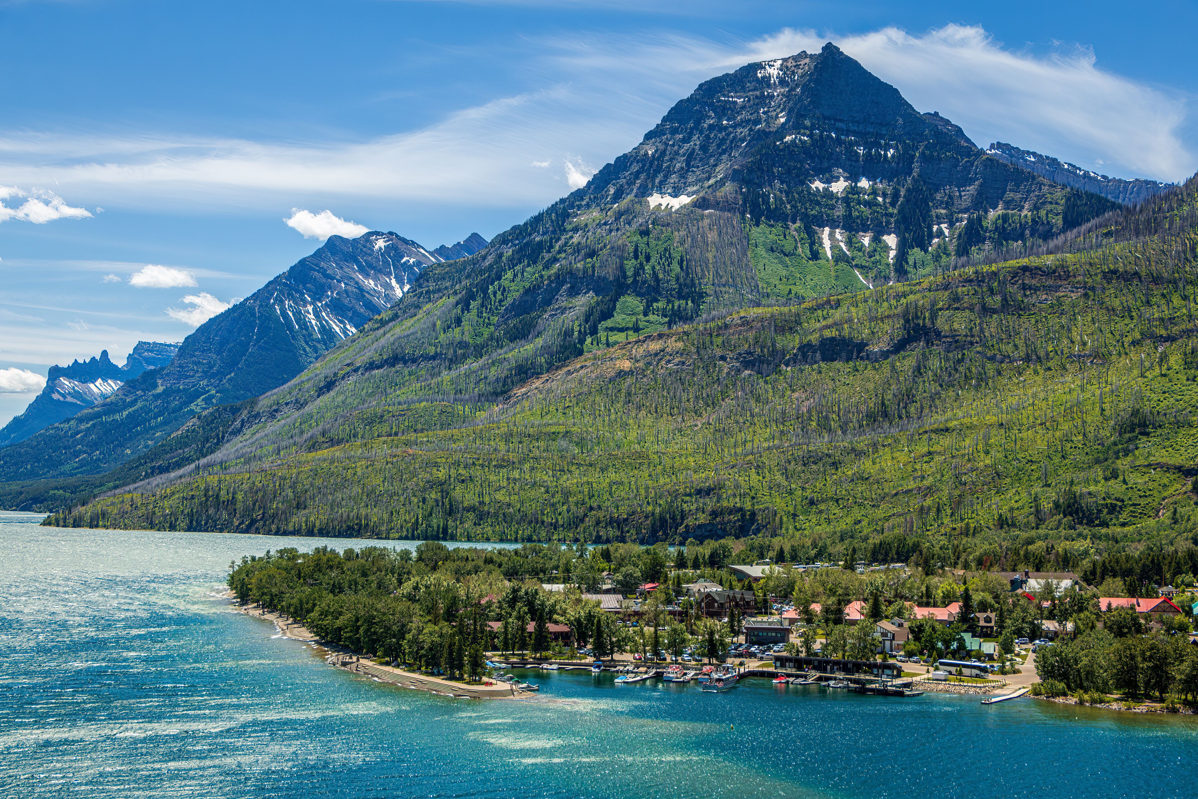 A mountain top called the Bears Hump at Waterton Lakes National Park, Canada. It is a beautiful, colorful mountain with a rainbow, blue sky, and clouds.