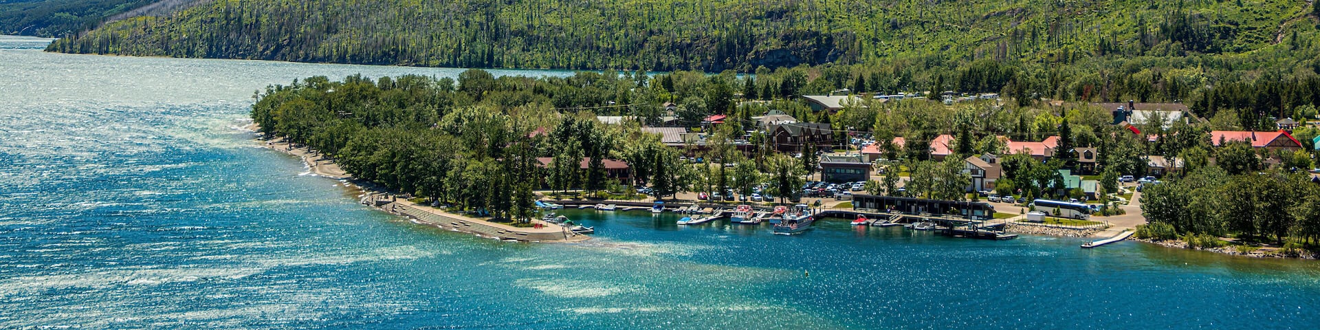 A mountain top called the Bears Hump at Waterton Lakes National Park, Canada. It is a beautiful, colorful mountain with a rainbow, blue sky, and clouds.