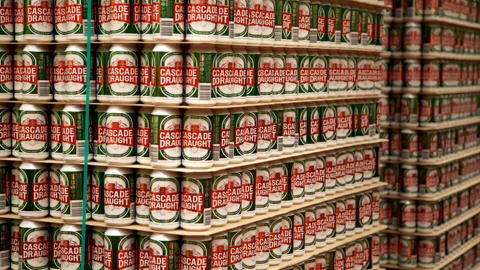 Stacks of Cascade Draught beer cans on shelves.
