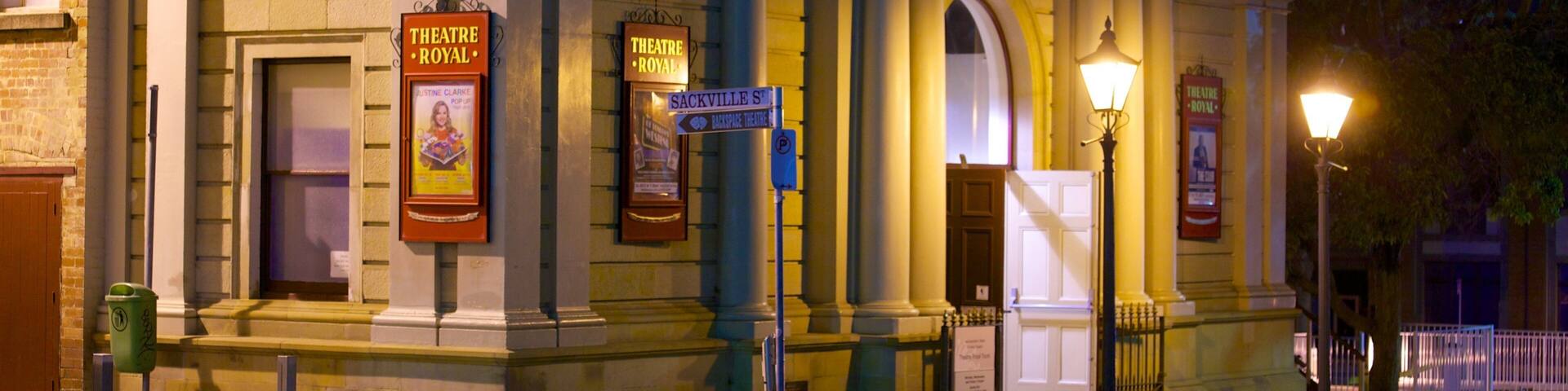 A historic theatre building with classical architecture, including columns and a pediment, and signs indicating its name and location.