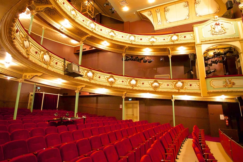 Un teatro ornamentado con asientos rojos y un balcón.