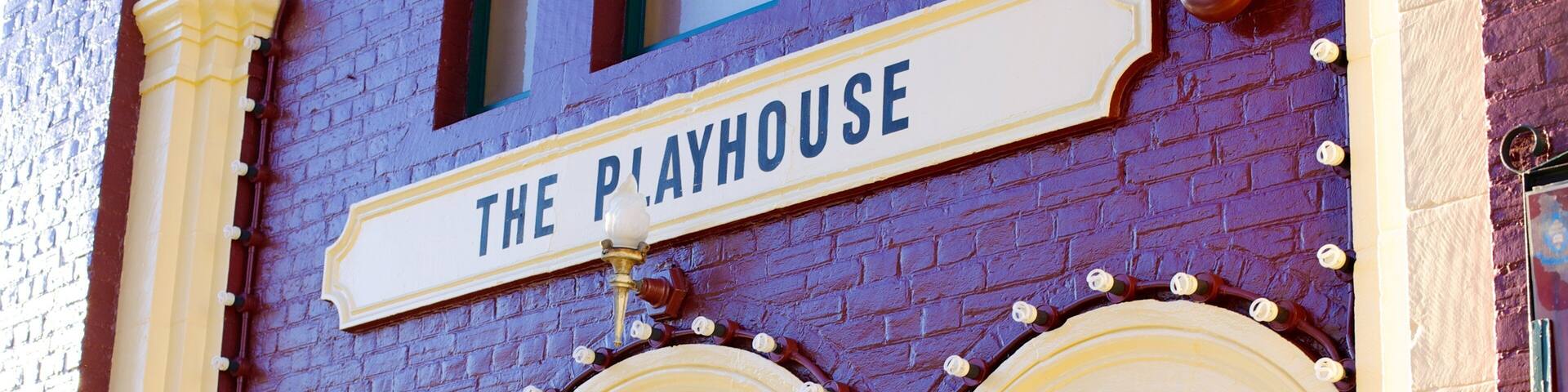 A building with a sign reading "THE PLAYHOUSE" above a set of three arched windows.