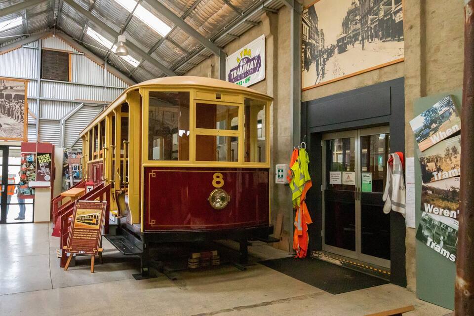 A vintage tram in a museum with historical displays and a tramway reunion sign.