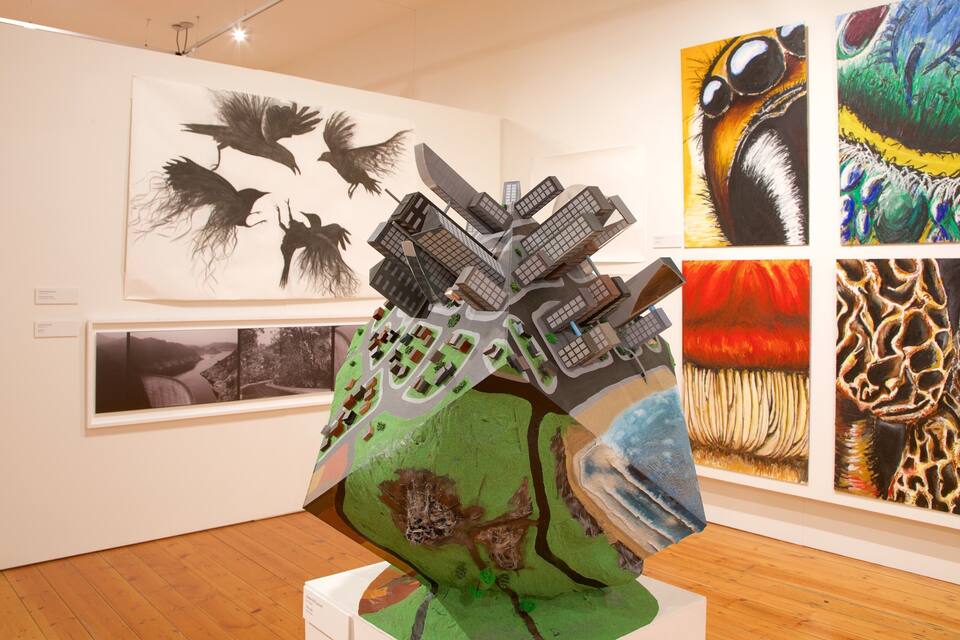 An art gallery with various artworks, including a sculpture of birds and a painting of a peacock.